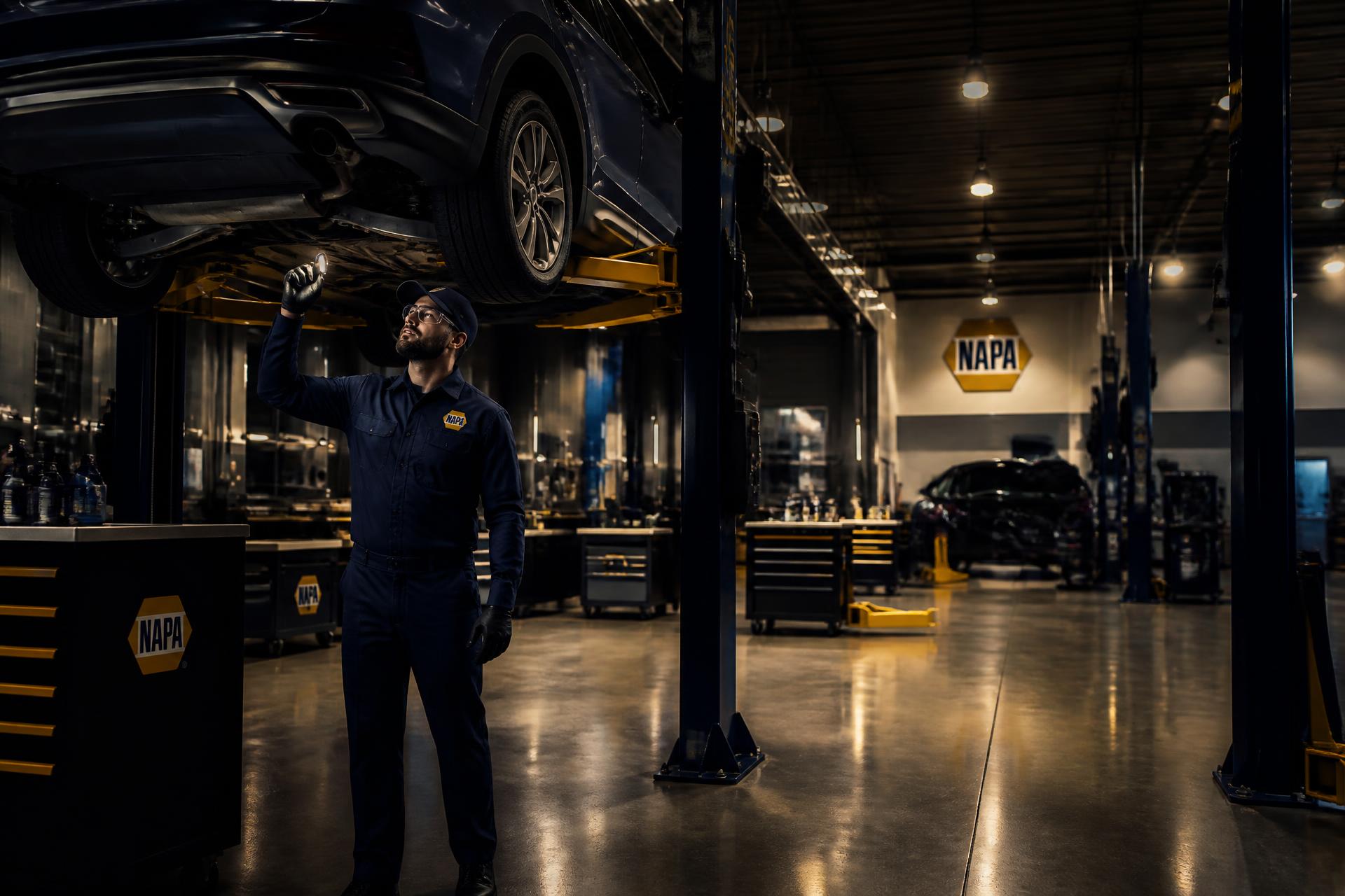 Professional NAPA AUTOPRO technician inspecting a vehicle on a lift in a modern service bay